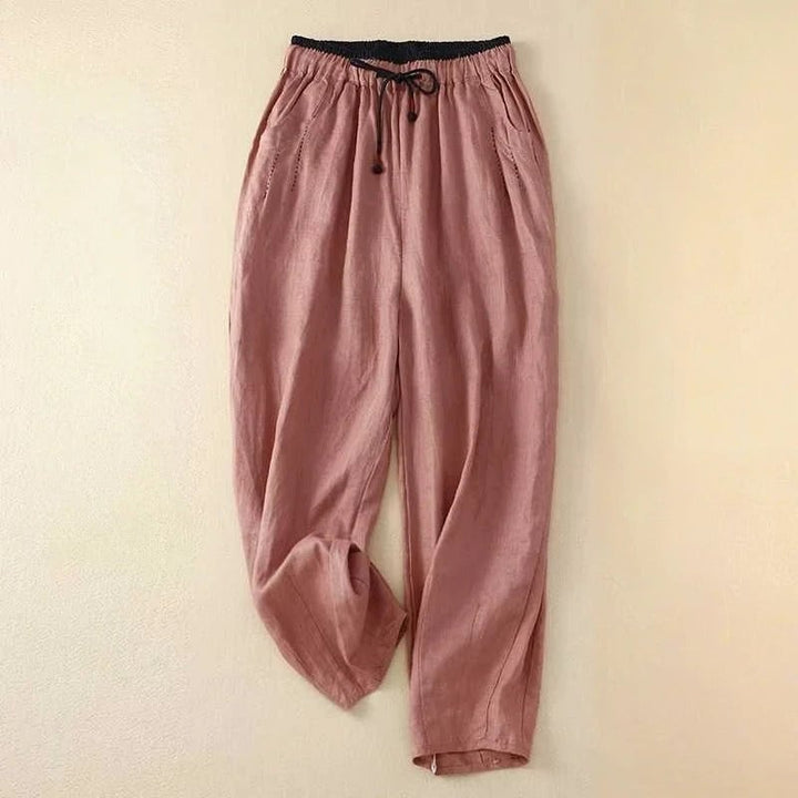 Woman styled in pink relaxed summer pants paired with a white tank top for a casual warm-weather look