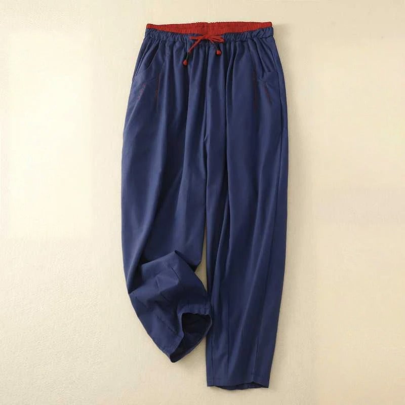 Flat lay of relaxed summer pants in all four colors: white, olive, pink, and navy blue