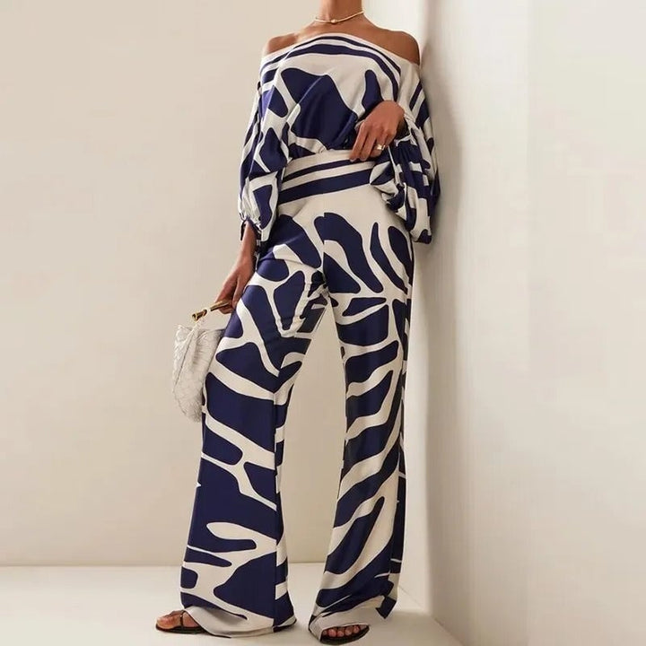 Woman wearing a navy and white abstract print off-shoulder batwing top and matching wide-leg pants from Florimay