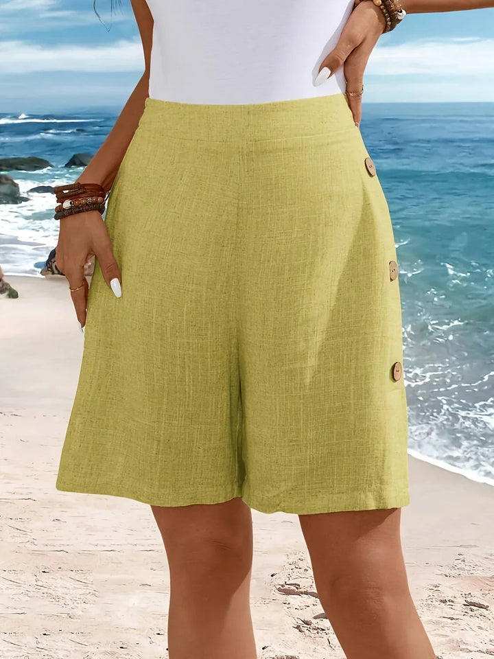 Full-length front view of relaxed-fit button shorts in green on a female model