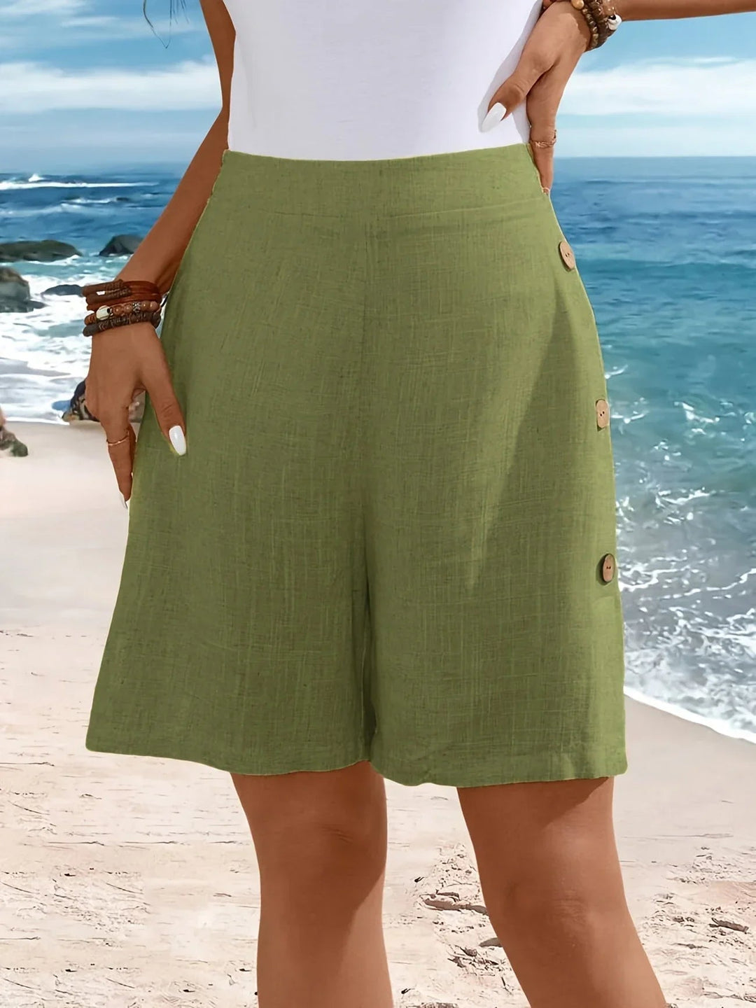 Flatlay of lightweight summer shorts in green showing fabric texture and button trim