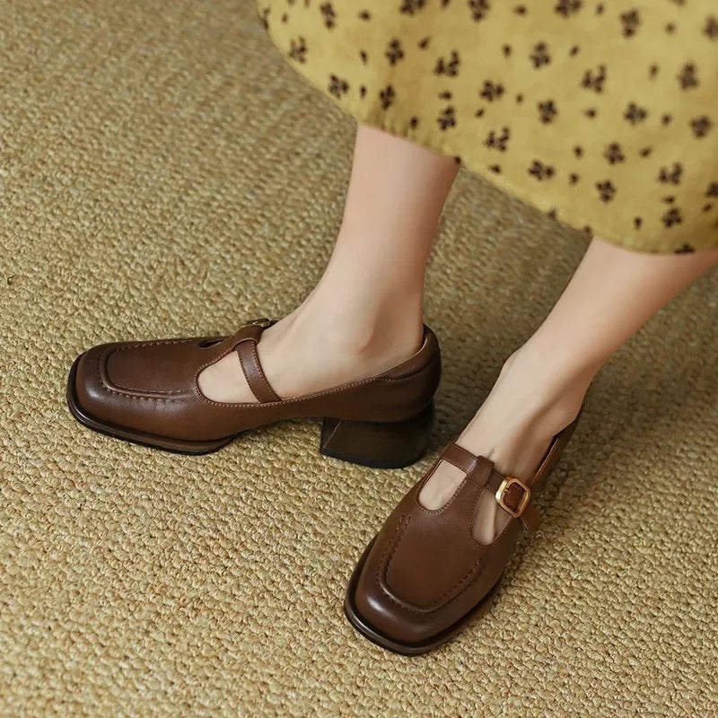 Close-up of gold-tone T-strap buckle closure on black mary jane shoe