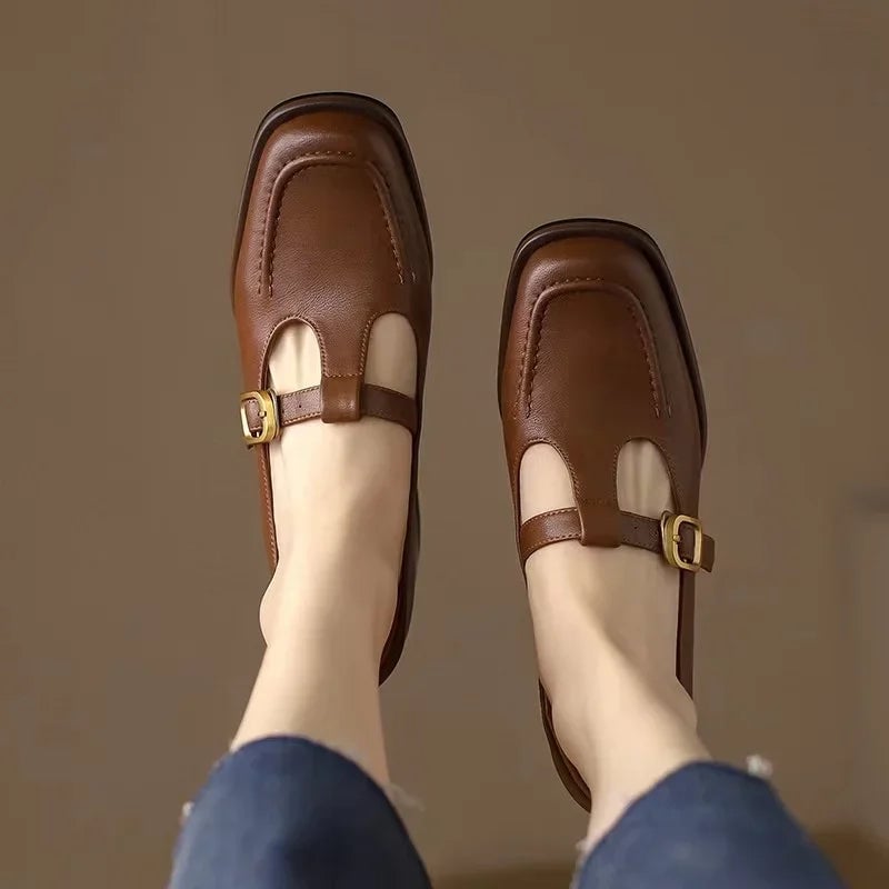 Close-up of gold buckle closure on brown T-strap mary jane shoe