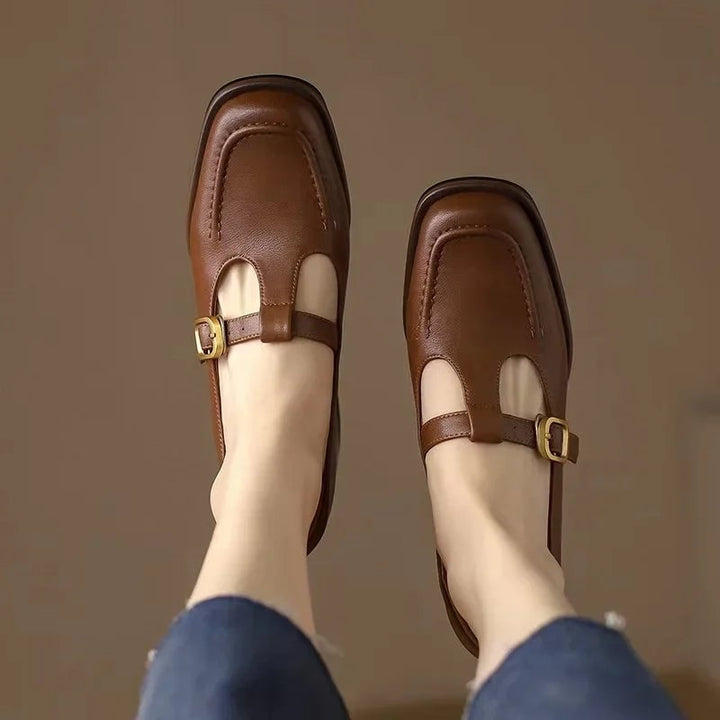 Close-up of gold buckle closure on brown T-strap mary jane shoe