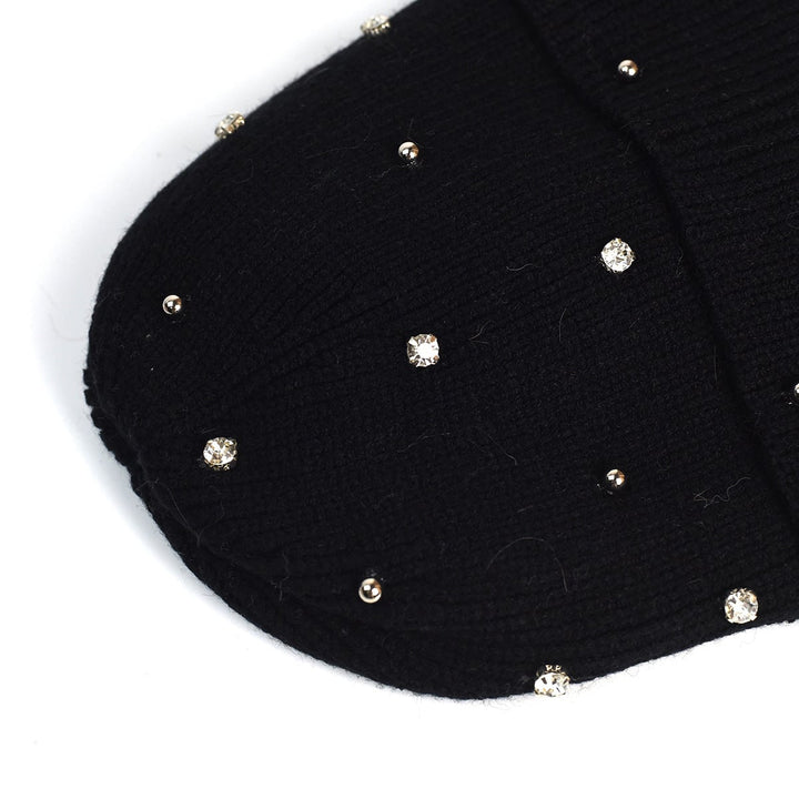 Side profile of a woman wearing a navy cozy beanie with beaded accents