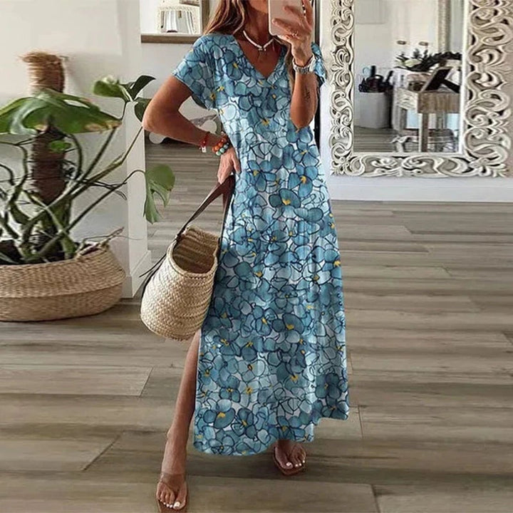 Woman wearing a blue watercolor floral boho maxi dress with V-neck, short sleeves, and side split