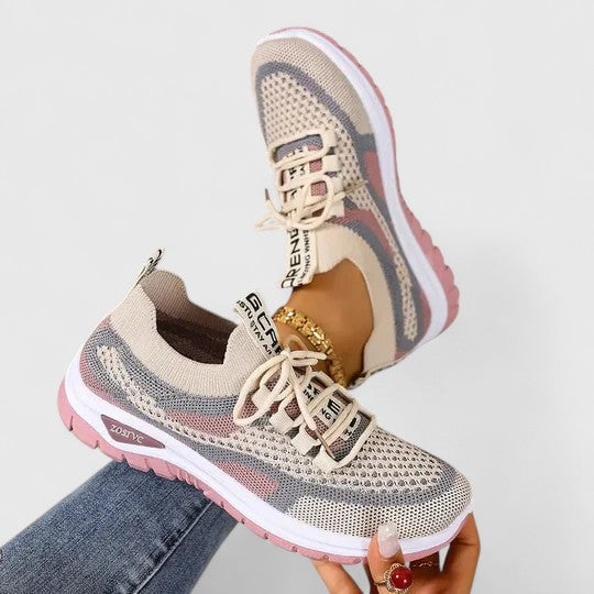 Close-up of graphic text lace detail and mesh upper on women's athletic sneakers