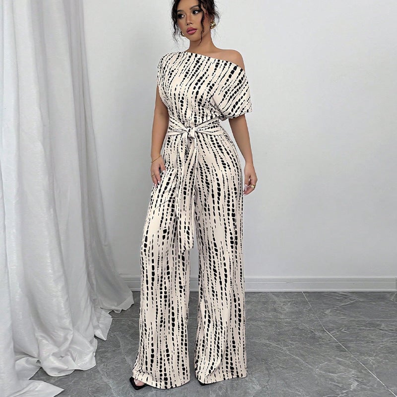 White printed wide-leg one-shoulder belted jumpsuit with black and cream abstract dot pattern, front view