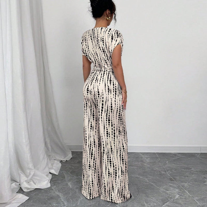 Side view of white one-shoulder wide-leg jumpsuit showing self-tie waist belt and sweeping leg silhouette