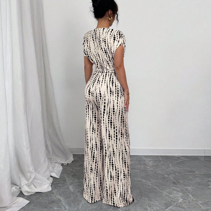 Side view of white one-shoulder wide-leg jumpsuit showing self-tie waist belt and sweeping leg silhouette