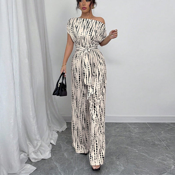 Close-up detail of the one-shoulder neckline and self-tie belt on the white printed wide-leg jumpsuit